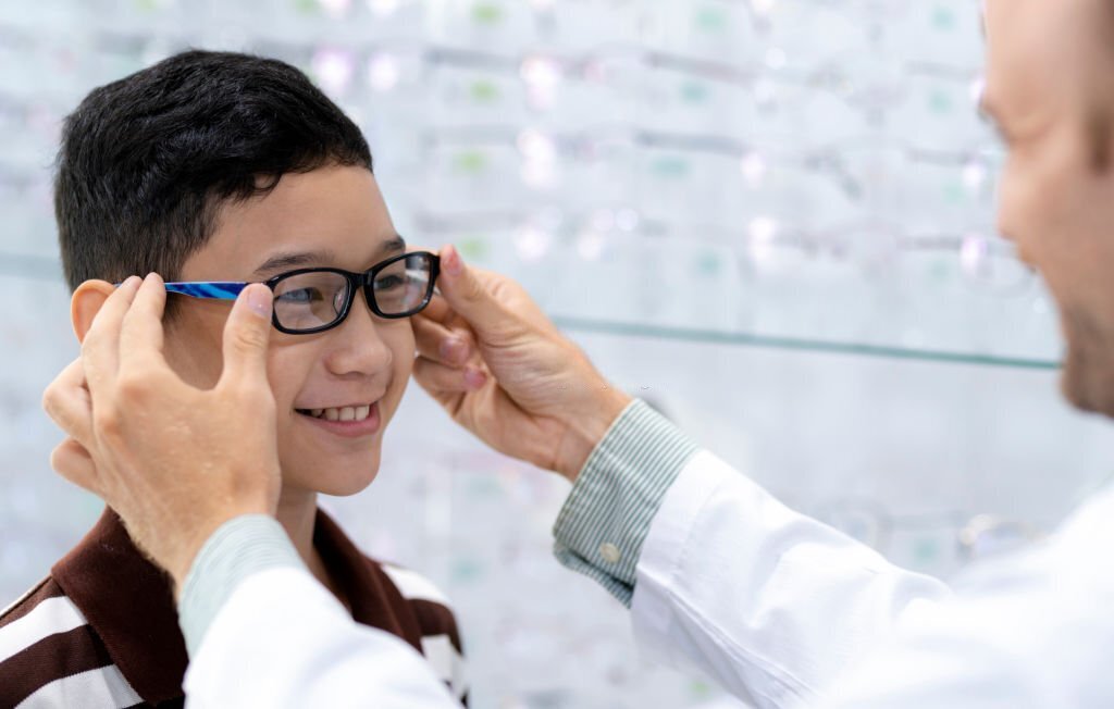 Ophthalmologist Puts New Eyeglasses On The Boy.